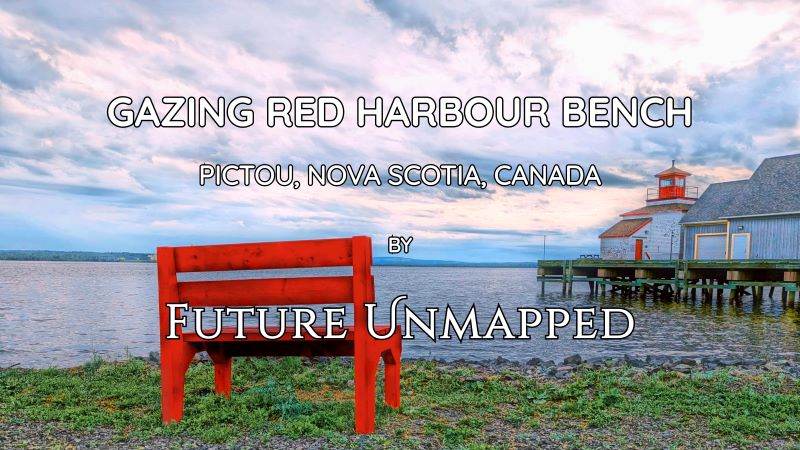 Lonesome red waterfront bench stares across sleepy harbour of old shipping port, at fisheries museum lighthouse in birthplace town.
