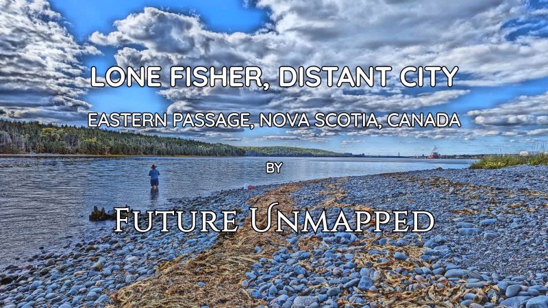 Sole fisher in shallows of wide, calm water - by vast, rocky, cobblestone beach - relaxes in provincial park, away from city hubbub and visible suspension bridge.